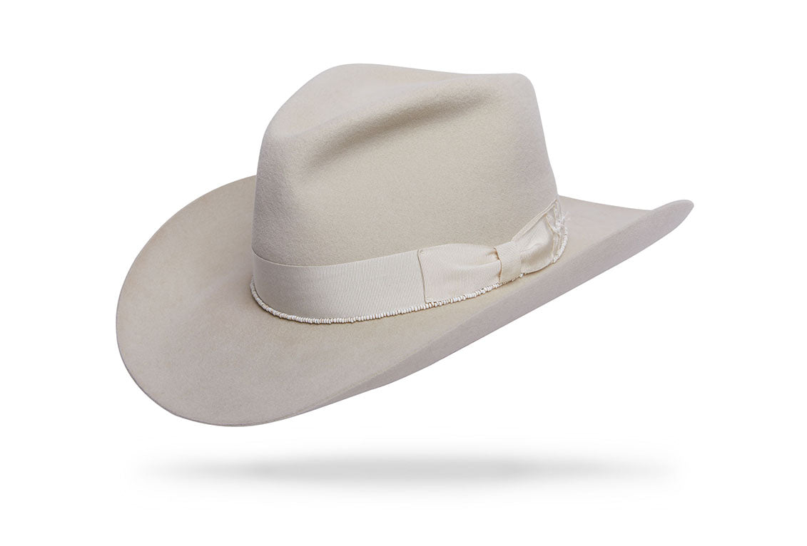 Design

Make a statement with our Western Cowboy Fellini Hat in Winter White, a timeless accessory that exudes sophistication and charm. Perfect for weddings and special occasions, this hat adds a touch of Western flair to any ensemble.

Material
100% Dressed Beaver fur felt sustainably acquired
Specifications
- 92 grams of 100% Beaver Fur Felt with a sharkskin finish- 3 1/2 snap brim and 4 1/4 center pinch C-crown. - A winter white bone beaver color with a tone-on-tone hatband and beads adornments  reverse 3 tip bow. - Handmade in our atelier in NYC.