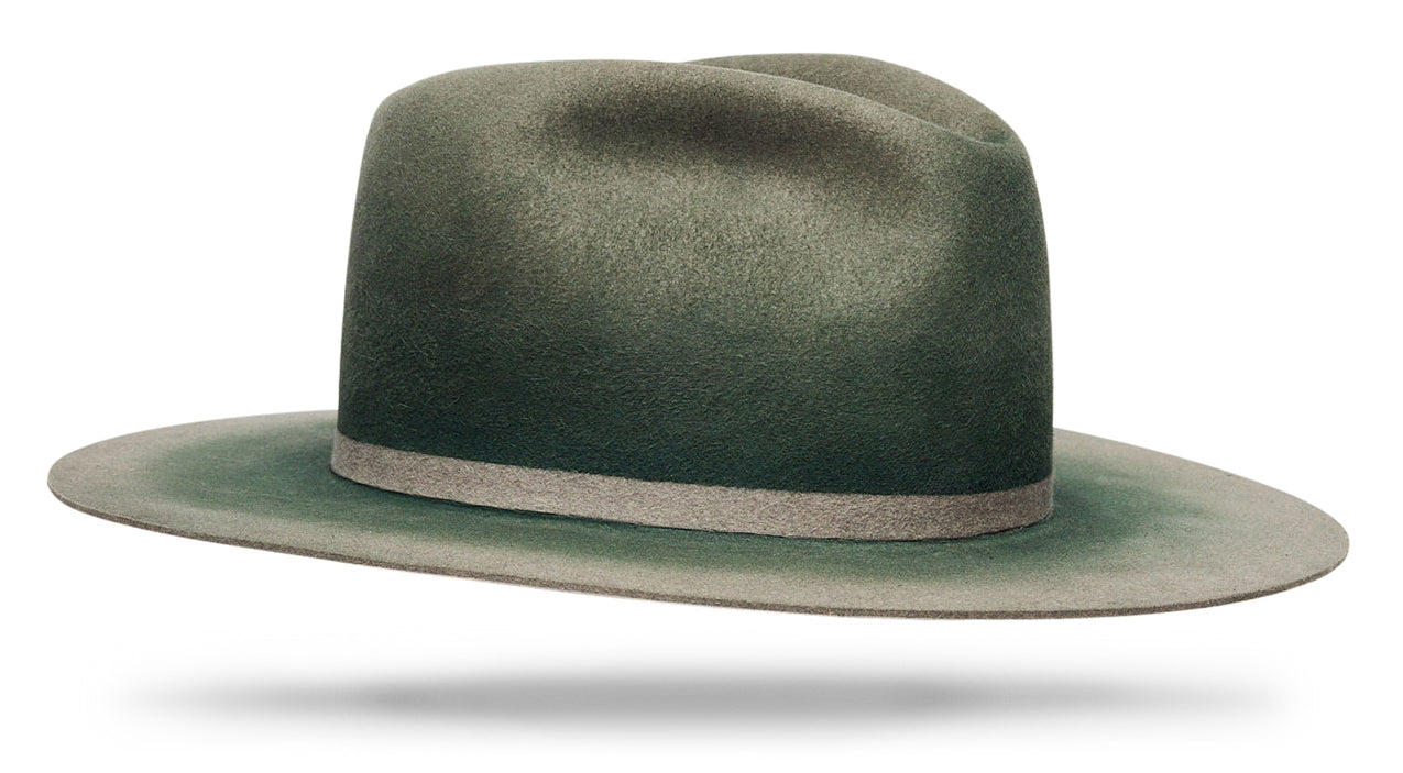 Design
Our classic Ash proportions, reimagined in a softer, packable beaver felt. Designed to fold, travel, and reshape beautifully, each piece is hand-dyed in our studio using layered techniques that give the Aegir Ash tone its subtle depth and character.Crafted from dressed beaver fur felt and finished with a 4” teardrop crown and 3.5” straight brim, this is a versatile, resilient hat made to be worn often and live well over time.
*** The model is wearing the blue ash with similar proportions. 
Material
100% Dressed Beaver fur Felt Hat sustainably acquired with natural green pigments. Natural dyeing minimizes the harmful effects on the surrounding environment. Our custom hats are hand-dyed by using plants and vegetable-based pigments.
Specifications
- A 4 Tear Drop Crown with a 3 1/2 straight brim- Triple hand dyed- With an invisible band - Handcrafted in our atelier in NYC. - Please allow 6 weeks to custom make this special piece.