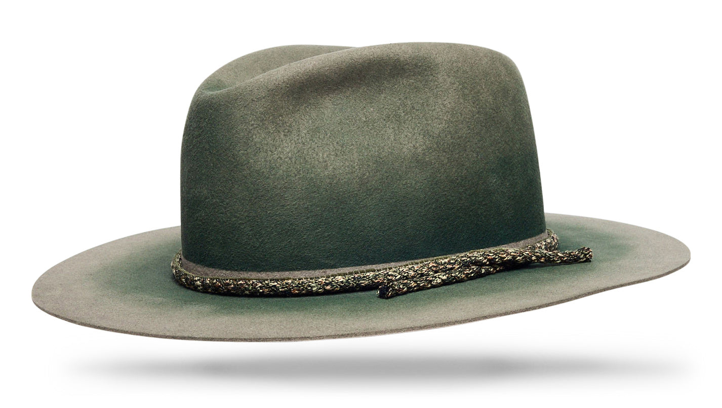 Design
Embrace the spirit of the sea with the AEGIR ASH hat, expertly crafted from 100% Beaver Fur Felt. This stunning piece features a rich green hue, achieved through a triple hand-dye process using Aegirine pigments, reflecting the natural beauty of the ocean's depths. With a 4 tear drop crown and a 3.5 straight brim, this hat combines timeless elegance with durability. The invisible band and hand-loomed vintage cord add refined details. A true workhorse, the AEGIR ASH is built to withstand the test of time, ensuring it remains a beloved piece in your wardrobe.
*** The model is wearing the blue ash with similar proportions. 
Material
100% Western Beaver fur Felt Hat sustainably acquired indigo dye treatment. Natural dyeing minimizes the harmful effects on the surrounding environment. Our custom hats are hand-dyed by using plants and vegetable-based pigments.
Specifications
- A 4 Tear Drop Crown with a 3 1/2 straight brim- Triple hand dyed- The invisible band and hand-loomed vintage cord add refined details.- Handcrafted in our atelier in NYC. - Please allow 6-8 weeks to custom make this special piece.