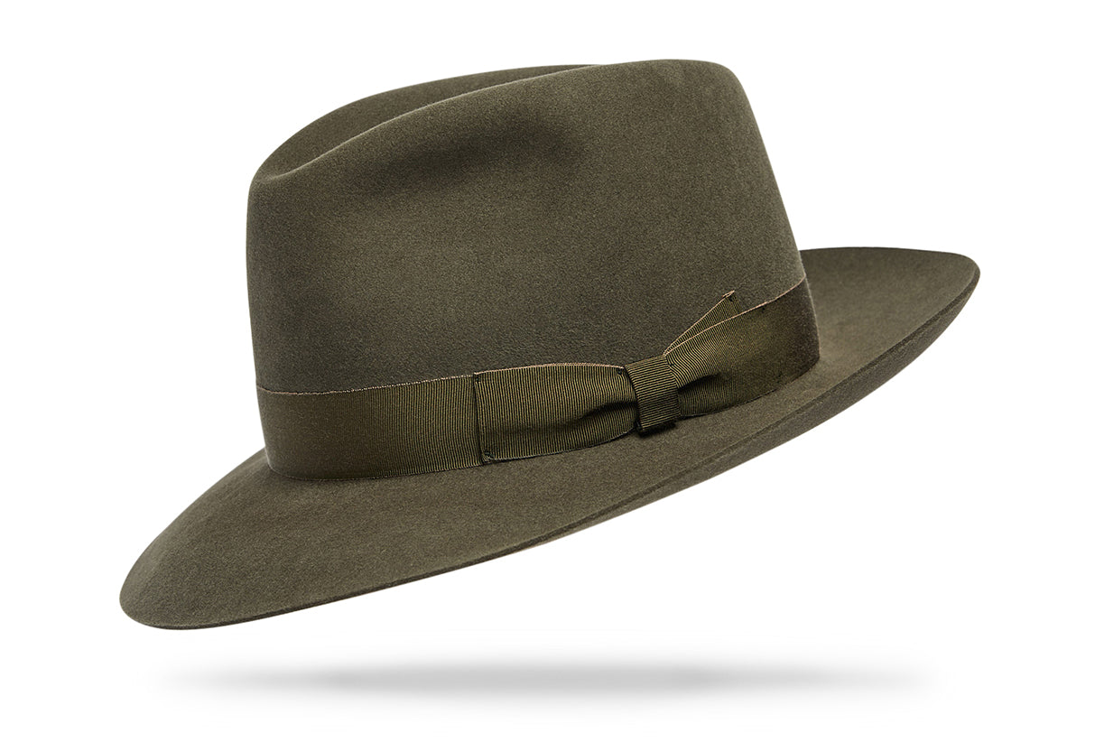 Design
A distinctive dress hat reminiscent of the times where the hat was a necessity for men and women. It boasts a 4” crown and a 2 ½” brim complete with a smart 1 ¼” hatband.
Material
100% Hare Fur Felt sustainably acquired
Specifications
100% Olive Hare Fur Felt 4” crown and a 2 ½” brim complete with a smart 1 ¼” hatband. Handcrafted in our NYC atelier